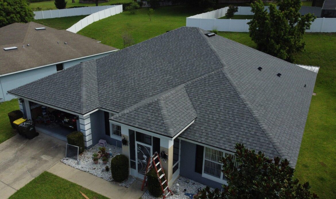 Aerial view of a residential home with a newly installed asphalt shingle roof in a quiet suburban neighborhood