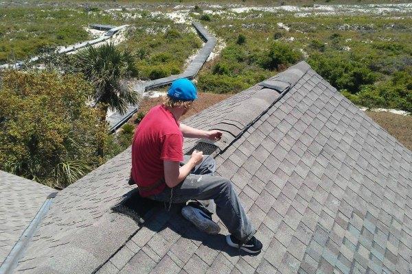 Worker sealing ridge vent on shingle roof
