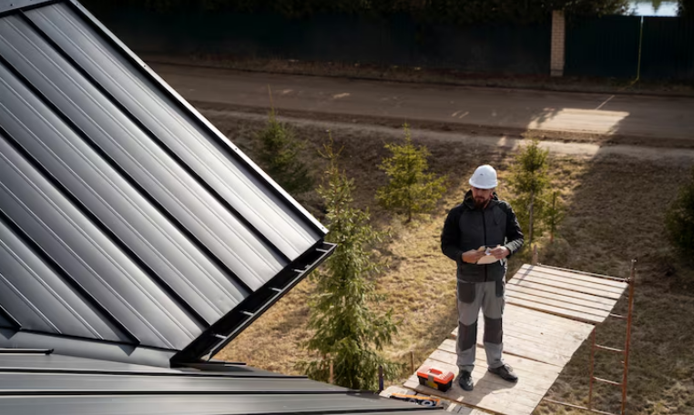 Man wearing a safety helmet inspecting metal roof panels outdoors
