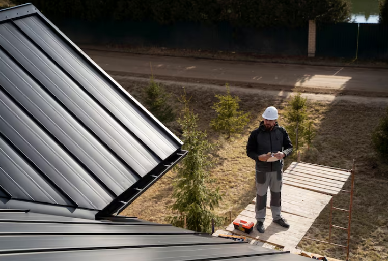 Man wearing a safety helmet inspecting metal roof panels outdoors