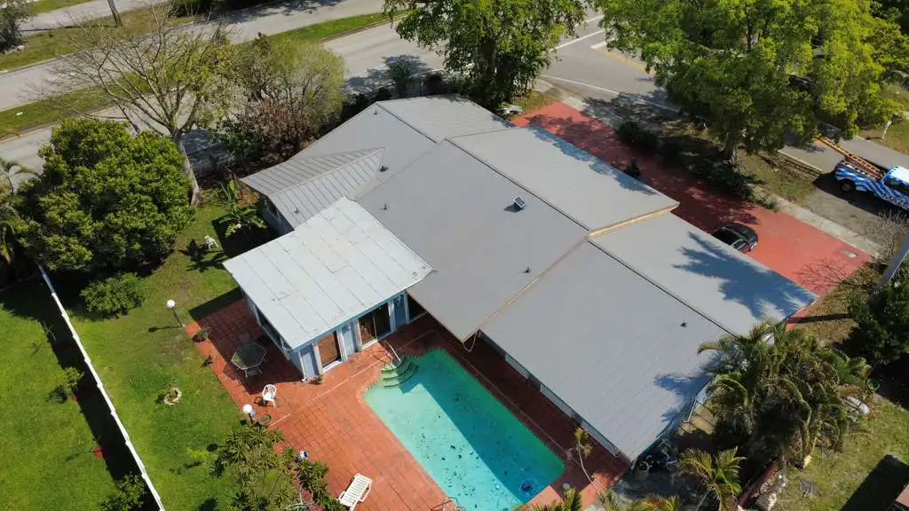 Aerial drone image of a modern metal roof installation overlooking a backyard pool and patio.
