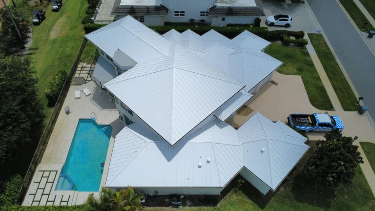 Top down drone view of a white standing seam metal roof and backyard pool.