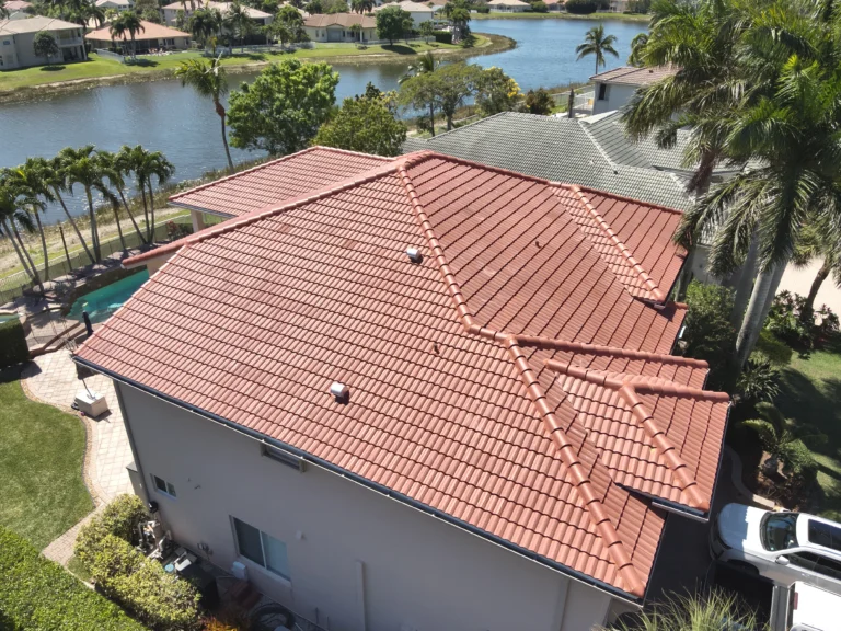 Aerial angle emphasizing the roof design, pool area, and neighboring houses along a water canal.