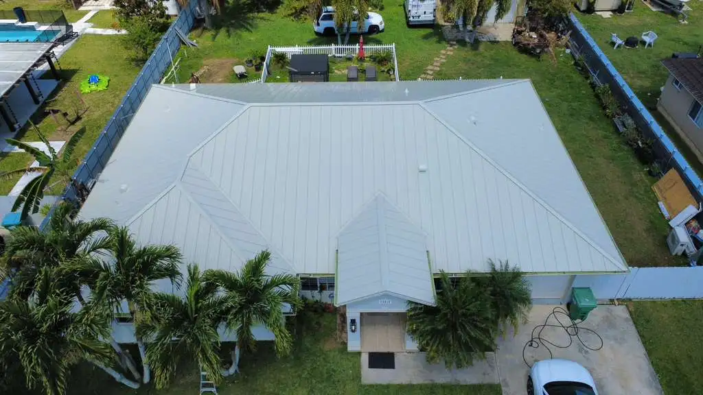 Top-down view of house with metal roof and yard