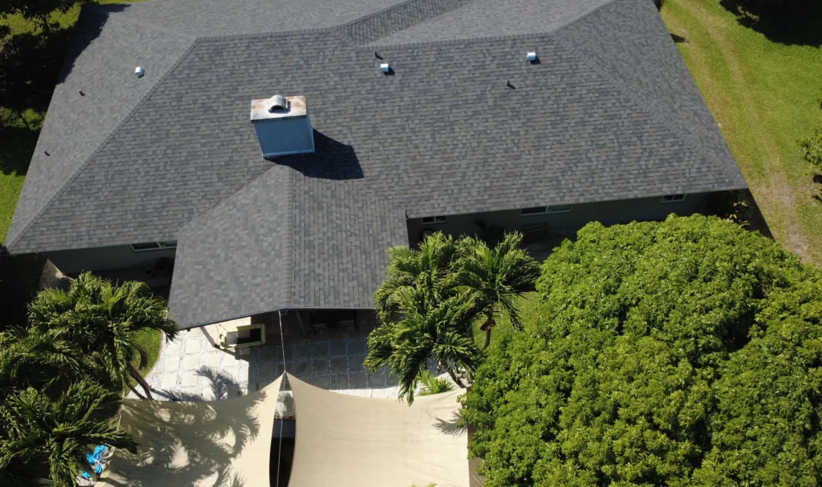 Aerial view of a completed gray asphalt shingle roof with chimney