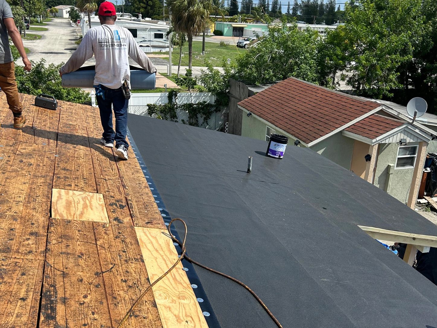 Roofing workers installing self-adhered underlayment over newly replaced plywood decking