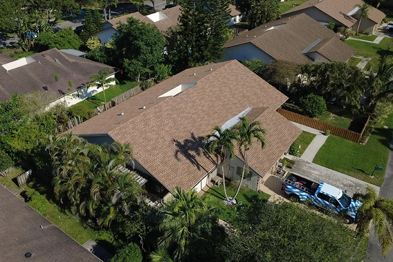 Aerial view of a Florida home with a new tan architectural shingle roof and a work truck on the driveway