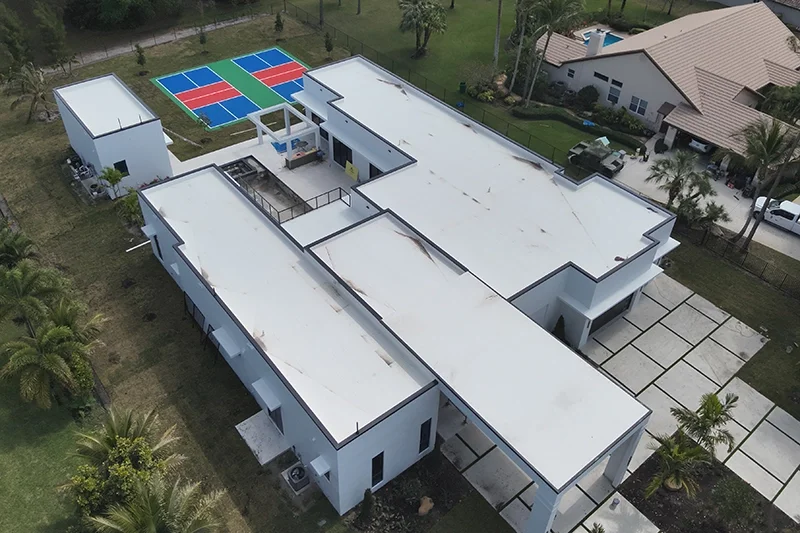 Aerial view of a modern Florida home with a large white flat roof and multiple roof sections
